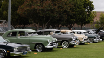 a row of classic cars parked on a grassy field