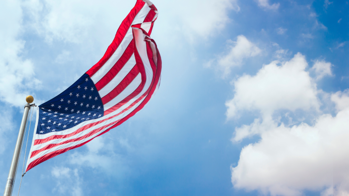 an american flag waving in the wind against a blue sky