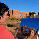 a person is painting on an easel in the desert
